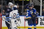 Le gardien des Jets de Winnipeg, Connor Hellebuyck, réagit alors que les Blues de St. Louis célèbrent leur deuxième but lors de la victoire de dimanche par les Blues au Enterprise Center. 