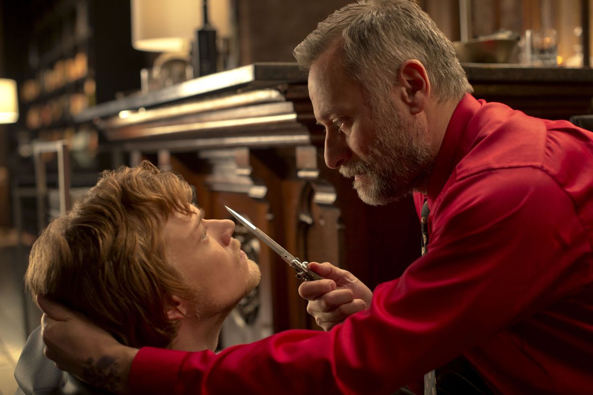 Viggo tient un couteau sur le visage de son fils Iosef dans John Wick