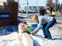 Brenda Baron apporte des fleurs au poste de la division ouest du service de police d'Edmonton le vendredi 17 mars 2023, alors qu'elle rend hommage au const.  Travis Jordan et Const.  Brett Ryan, qui ont été tués dans l'exercice de leurs fonctions jeudi.  Le gendre de Baron est policier à la Division Ouest.