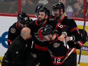 L'attaquant des Sénateurs Derick Brassard regarde vers le ciel alors que ses coéquipiers Shane Pinto, Alex DeBrincat et Austin Watson et le thérapeute du sport Dom Nicoletta l'aident à sortir de la glace après une blessure en deuxième période.