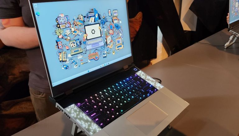 head on image of open Framework gaming laptop on presentation floor, abstract desktop background in Windows with RGB keyboard, speakers on side, chrome furnishing and slim black bezels