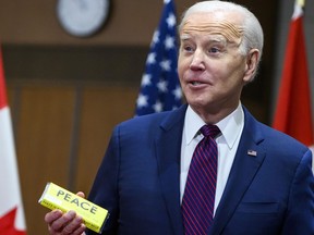 Le président américain Joe Biden réagit en tenant une barre de chocolat qui lui a été offerte sur la Colline du Parlement à Ottawa, le 24 mars 2023