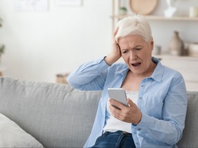 Concept d'escroqueries mobiles.  Femme âgée choquée regardant l'écran du smartphone dans la frustration