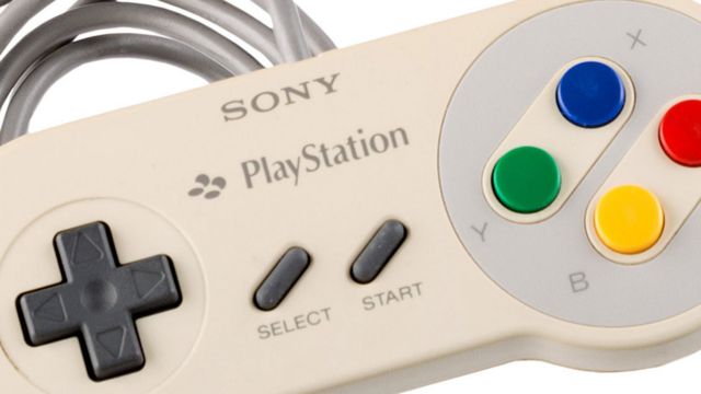 Un contrôleur de marque Sony PlayStation dans la forme et le design du contrôleur SNES.  Il présente la même disposition des boutons que le SNES avec des boutons directionnels à gauche, des boutons de démarrage et de sélection au centre et les boutons B (jaune), A (rouge), X (bleu) et Y (vert) à droite.