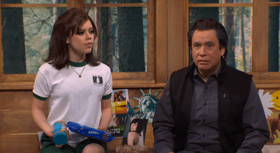 Fred Armisen and Jenna Ortega sitting on a bed and talking during an SNL sketch.