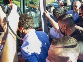 Des rochers frappent le chef libéral Justin Trudeau dans le dos et la tête alors qu'il monte dans un bus à la fin d'un arrêt de campagne à la London Brewing Co-op à Londres le 6 septembre 2021. (Derek Ruttan/The London Free Press)