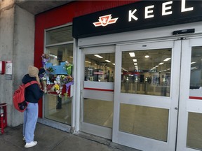 Une femme dépose des fleurs sur un mémorial de fortune à la station de métro Keele de la TTC pour Gabriel Magalhaes, qui a été poignardé à mort deux jours plus tôt lors d'une attaque non provoquée, le 27 mars 2023.