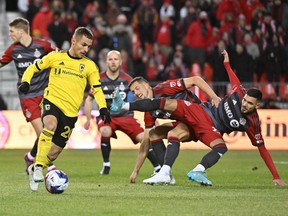 Le milieu de terrain du Columbus Crew Alexandru Matan (à gauche) contrôle le ballon alors que le défenseur du Toronto FC Raoul Petretta (28 ans) entre en collision avec un coéquipier en première mi-temps au BMO Field hier soir.