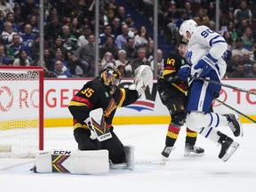 Ryan O'Reilly (90 ans) des Maple Leafs de Toronto est frappé par la rondelle devant le gardien des Canucks de Vancouver Thatcher Demko (35 ans) alors que Quinn Hughes (43 ans) regarde pendant la deuxième période d'un match de hockey de la LNH à Vancouver, le samedi mars. 4, 2023.