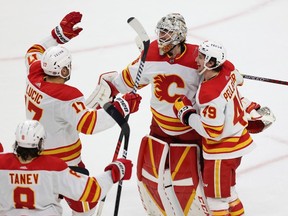 Le gardien de but des Flames de Calgary, Jacob Markstrom, est entouré de coéquipiers pour célébrer la victoire 1-0 de l'équipe lors d'une fusillade contre le Wild Xcel Energy Center du Minnesota à St. Paul, Minnesota, le mardi 7 mars 2023.