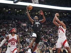 L'attaquant des LA Clippers Kawhi Leonard (2) monte pour faire un panier contre le garde des Raptors de Toronto Gary Trent Jr. (33) et l'attaquant Scottie Barnes (4) à la Scotiabank Arena.