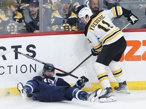 L'attaquant des Jets de Winnipeg Mark Scheifele (à gauche) est trébuché par Trent Frederic des Bruins de Boston lors de la première période à Winnipeg le 16 mars 2023.