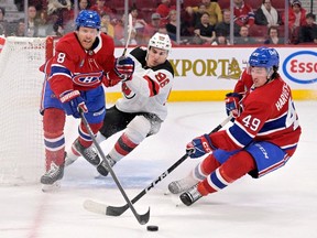 Le défenseur des Canadiens Mike Matheson (8) et l'attaquant Rafael Harvey-Pinard (49) empêchent l'attaquant des Devils du New Jersey Jack Hughes (86) de marquer dans un filet vide lors de la troisième période au Centre Bell, le samedi 11 mars 2023, à Montréal .