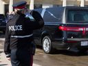 Un agent du Service de police d'Edmonton salue l'arrivée d'un cortège avec les corps du const.  Travis Jordan et Const.  Brett Ryan au Serenity Funeral Home à Edmonton le mardi 21 mars 2023. 