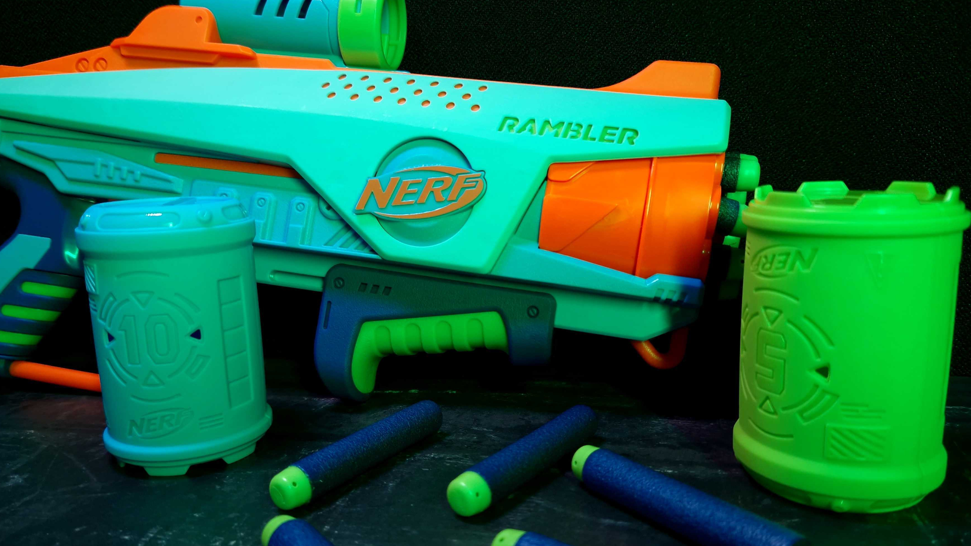 Le Nerf Elite Jr. Rambler du Rookie Pack avec fléchettes et cibles, disposé sur un fond sombre