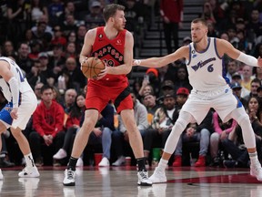 Le centre des Raptors Jakob Poeltl contrôle le ballon alors que Kristaps Porzingis du Washington Wizard tente de défendre au cours du quatrième quart à la Scotiabank Arena dimanche.