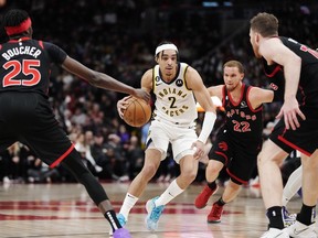 Le garde des Indiana Pacers Andrew Nembhard (2) conduit entre Chris Boucher des Raptors (25), Malachi Flynn (22) et Jakob Poeltl (19) au cours de la seconde mi-temps à Toronto le mercredi 22 mars 2023.