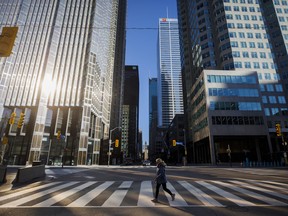 Une femme traverse la rue pendant les heures de trajet du matin dans le quartier financier de Toronto.