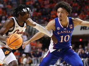 Le gardien des Oklahoma State Cowboys Caleb Asberry (5) tente de dépasser l'attaquant des Kansas Jayhawks Jalen Wilson (10) lors d'un match de basket-ball universitaire masculin entre les Oklahoma State University Cowboys et les Kansas Jayhawks à Gallagher-Iba Arena à Stillwater, Okla., Mardi, 14 février 2023.