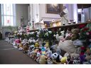 Des fleurs et des ours en peluche bordent la façade de l'église Ste-Rose-de-Lima de Laval le vendredi 10 février 2023 lors d'une messe communautaire à la mémoire des deux enfants tués et blessés dans l'accident d'autobus de mercredi.