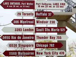 Un poteau de signalisation à St. Catharines, Ont.  montre les distances en miles nautiques aux ports proches et lointains.  De nombreuses petites villes de l'Ontario sont les plus touchées par la correction du logement.