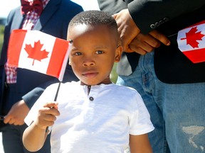 Brian Egbe agite un drapeau à Calgary lors d'une première cérémonie de citoyenneté en personne à l'amphithéâtre BMO du Stampede Park le 11 juillet 2022. Darren Makowichuk/Postmedia