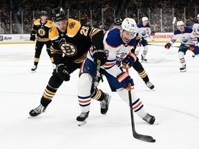 L'ailier gauche des Oilers d'Edmonton Zach Hyman (18 ans) contrôle la rondelle devant le défenseur des Bruins de Boston Brandon Carlo (25 ans) au cours de la deuxième période au TD Garden.