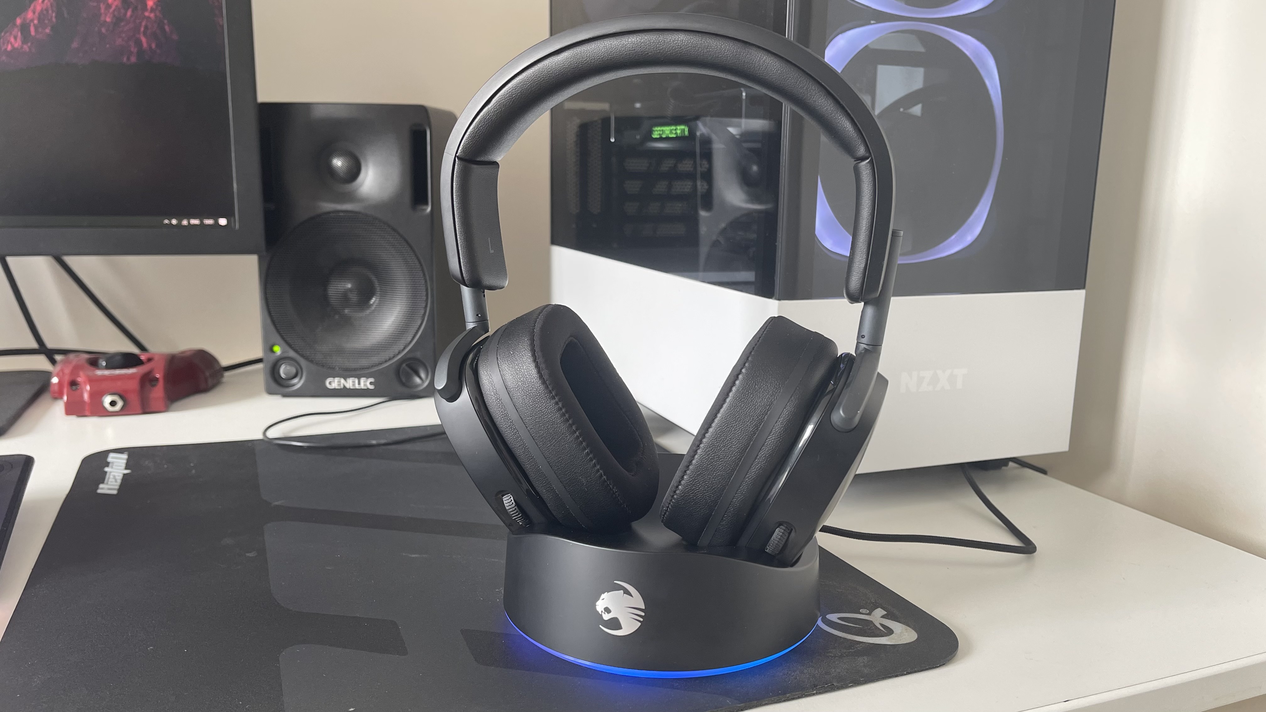 Casque Roccat Syn Max Air dans un socle de chargement sur un bureau de jeu à côté d'un PC