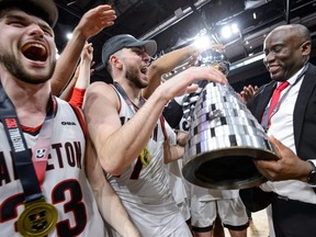 Halifax, Nouvelle-Écosse - 12 mars 2023 : match de championnat national de la médaille d'or de basket-ball USports Men's Final 8 entre Carleton Ravens et St FX XMen au Scotiabank Centre à Halifax, en Nouvelle-Écosse.  De gauche à droite, Connor Vreeken, Gebrael Samaha et l'entraîneur Taffe Charles célèbrent après la victoire en double prolongation.