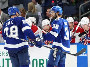 Les joueurs du Lightning de Tampa Bay Brandon Hagel (38) et Ian Cole (28) célèbrent après le but de Hagel samedi à Tampa, avec Jonathan Drouin (au centre) des Canadiens qui regarde depuis le banc.