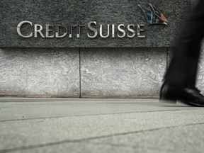 Un piéton passe devant un logo du Credit Suisse à l'extérieur de son immeuble de bureaux à Hong Kong, Chine.