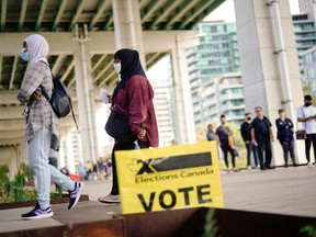 Des gens font la queue devant un bureau de vote pour voter aux élections fédérales, à Toronto, le 20 septembre 2021.