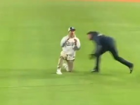 Un jeune homme a sauté sur le champ extérieur du Dodger Stadium pour proposer à sa petite amie dans les gradins, et a été aplati par la sécurité lors de la journée d'ouverture de la MLB jeudi.