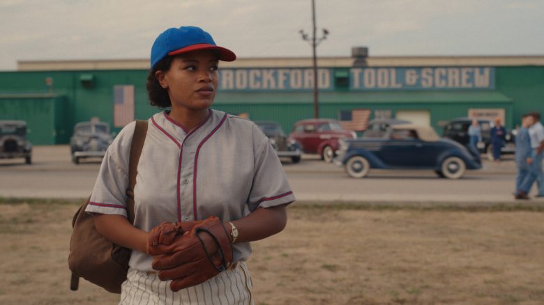 A woman in baseball uniform standing at the edge of a field; still from "A League of Their Own."