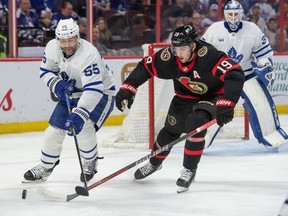 Le défenseur des Maple Leafs Mark Giordano (55) et l'ailier droit des Sénateurs Drake Batherson (19) se battent pour la rondelle en première période.