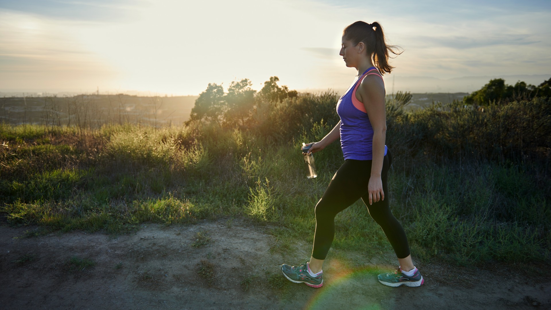 Femme partant pour une séance d'entraînement à pied dans la nature portant des vêtements de sport