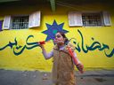 Un enfant souffle des bulles de savon alors qu'elle se tient devant un mur, peint de couleurs vives et de calligraphie arabe qui se lit 