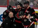 Shane Pinto, Alex DeBrincat et Austin Watson des Sénateurs d'Ottawa aident à sortir de la glace leur coéquipier blessé Derick Brassard lors de la deuxième période contre les Flyers de Philadelphie le jeudi 30 mars 2023 à Ottawa.  La blessure a mis fin à la saison de Brassard.