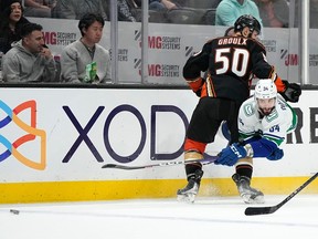 L'ailier gauche des Canucks de Vancouver Phillip Di Giuseppe, à droite, passe la rondelle sous la pression du centre des Ducks d'Anaheim Benoit-Olivier Groulx lors de la deuxième période, le mardi 11 avril 2023, à Anaheim, en Californie.