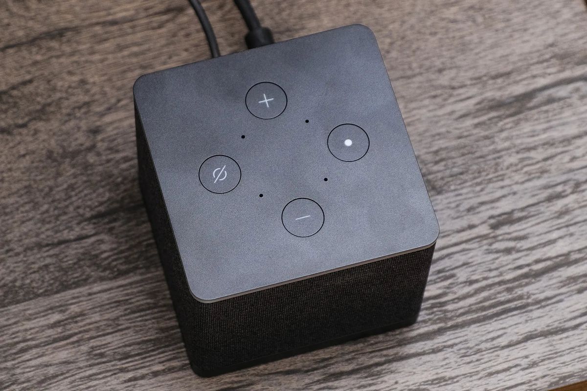 Une vue de haut en bas du cube Amazon Fire TV, montrant ses microphones, plus quatre boutons pour régler le volume et éteindre les microphones.