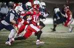 Les Red Leafs de l'Université Simon Fraser, Robert Meadors, dirigent le ballon sur le terrain tout en essayant d'éviter d'être plaqués par Luke Burton-Krahn des rivaux de la ville, les Thunderbirds de l'UBC, lors du 34e Shrum Bowl à SFU le vendredi 2 décembre 2022.