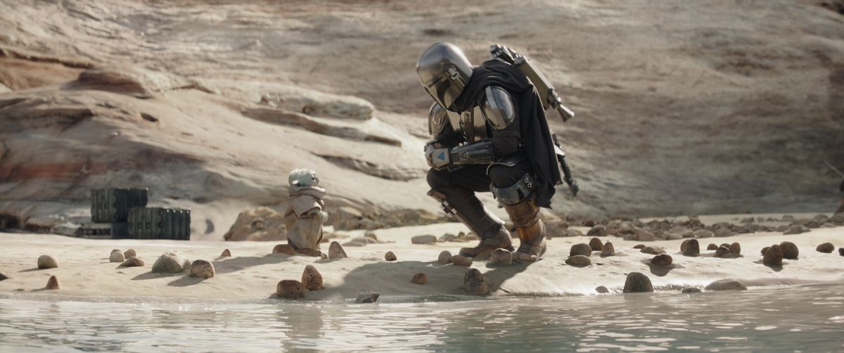 Le Mandalorien s'accroupit à côté de Grogu près de l'eau dans la saison 3 de The Mandalorian.