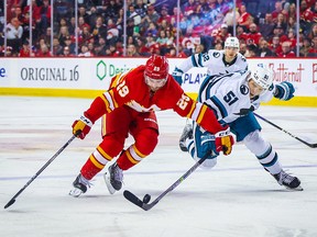 Le centre des Flames de Calgary Dillon Dube (29 ans) et le défenseur des Sharks de San Jose Radim Simek (51 ans) se battent pour la rondelle au cours de la troisième période au Scotiabank Saddledome de Calgary le 12 avril 2023.