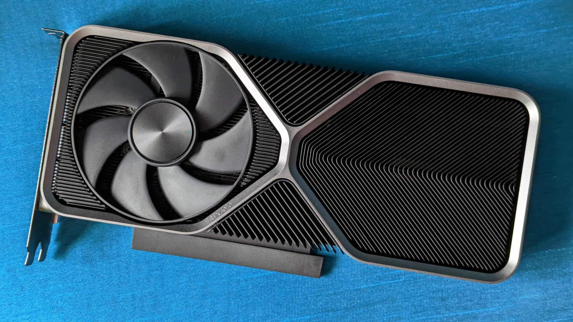 Test Nvidia GeForce RTX 4070 : Une carte graphique Founders Edition reposant sur un fond bleu