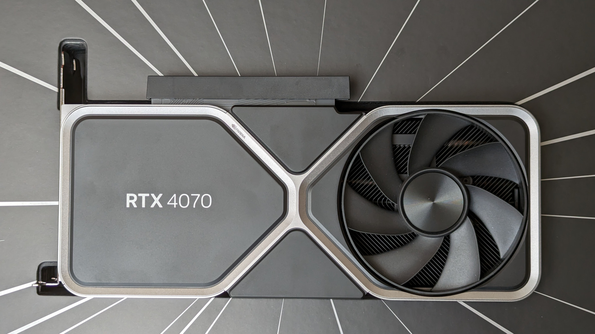 Revue Nvidia GeForce RTX 4070 : Une carte graphique Founders Edition reposant dans son emballage de vente au détail, entourée de stries argentées