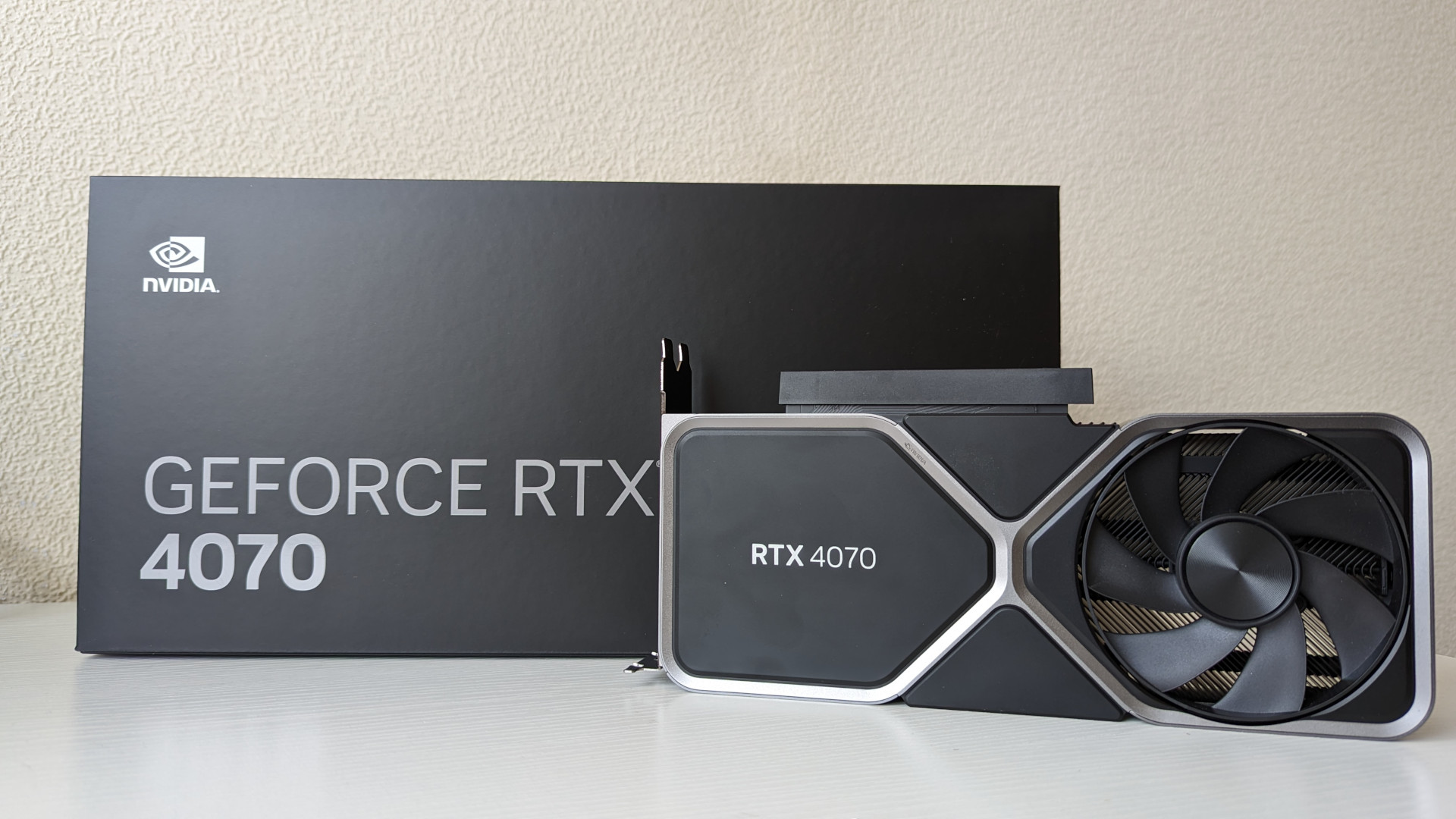 Revue Nvidia GeForce RTX 4070 : Une carte graphique Founders Edition adjacente à son emballage de vente au détail