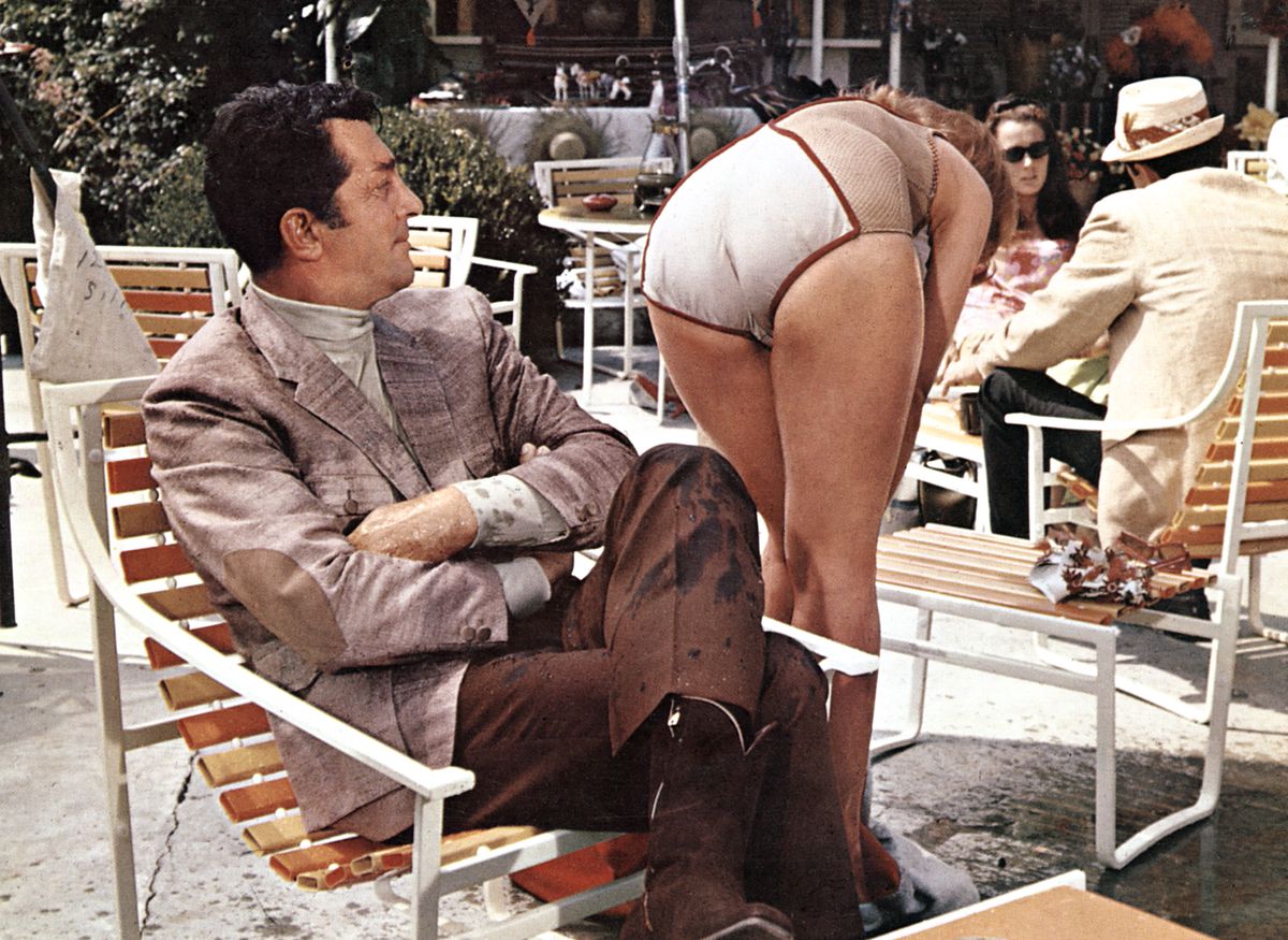 Une femme en maillot de bain se penche devant Matt Helm qui regarde ses fesses d'un air approbateur