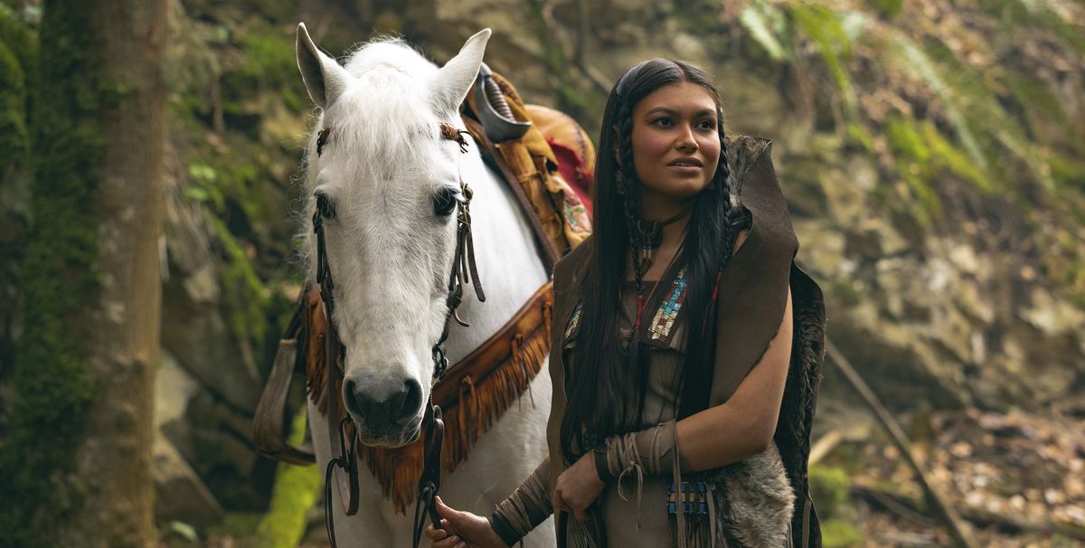 Alyssa Wapanatâhk comme Tiger Lily dans Peter Pan &  Wendy, debout à côté d'un cheval blanc dans une forêt