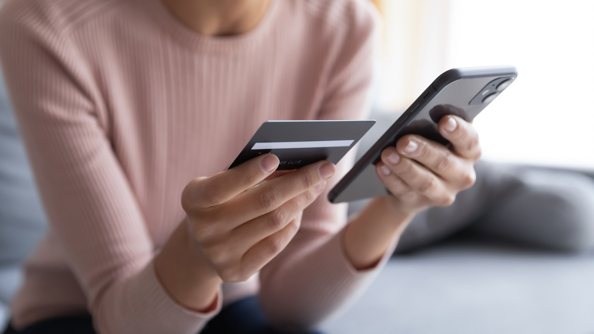 Personne tenant une carte de crédit dans une main et un téléphone dans l'autre