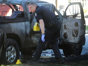 Un policier de Vancouver cherche des preuves dans un véhicule incendié à Penticton et Charles à la suite d'une fusillade dans le parking de l'hôtel Fairmont Pacific Rim à Vancouver.  Les voitures de fuite en flammes sont une caractéristique des gangs de la Colombie-Britannique.